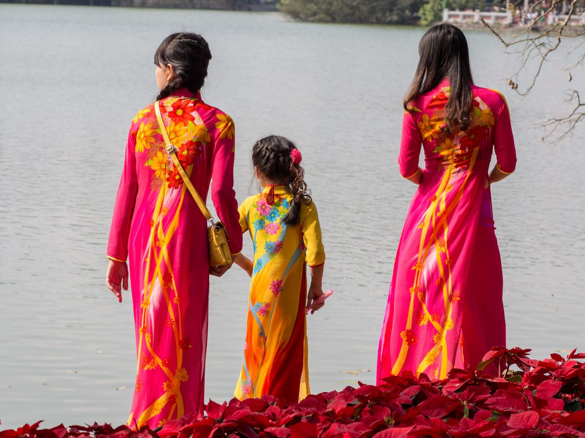 Girls in colorful traditional dresses walking along lake