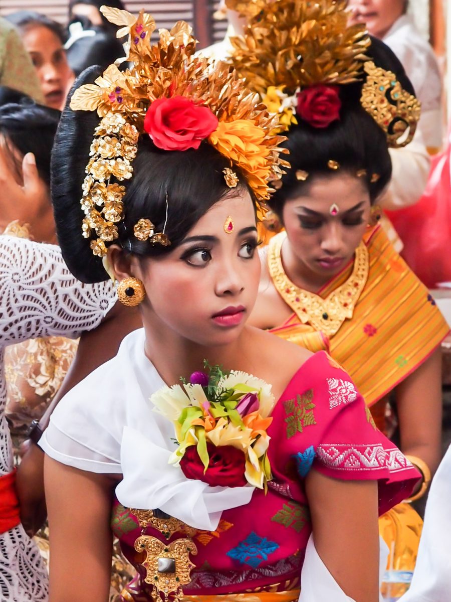Girl in elaborate dress and gold headdress looking nervous at ceremony