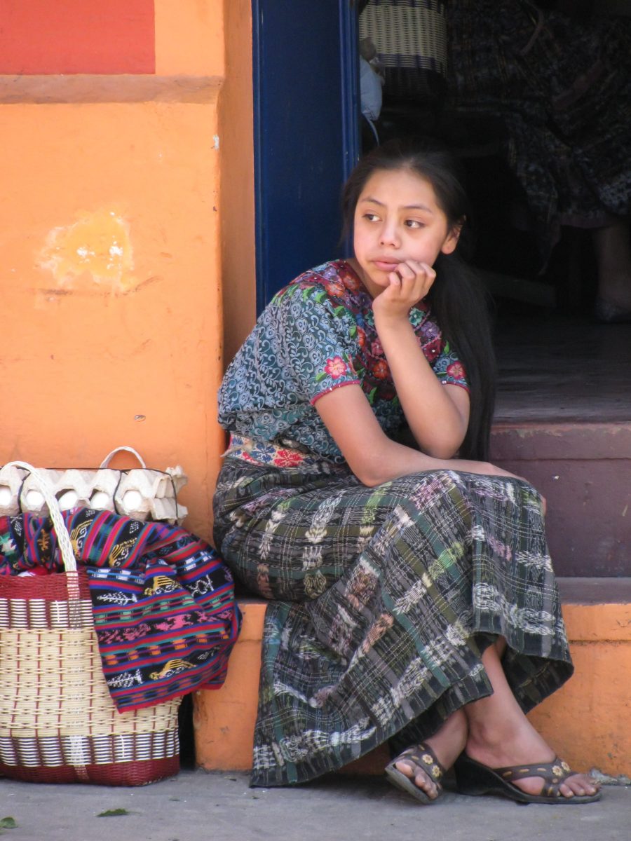Mayan girl sitting on stoop with market basket