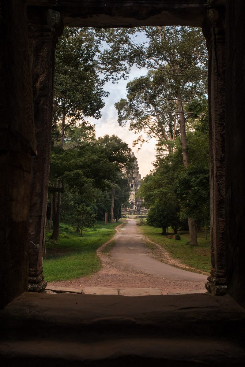 View out crumbling doorway along path to Angkor Wat temple in the trees