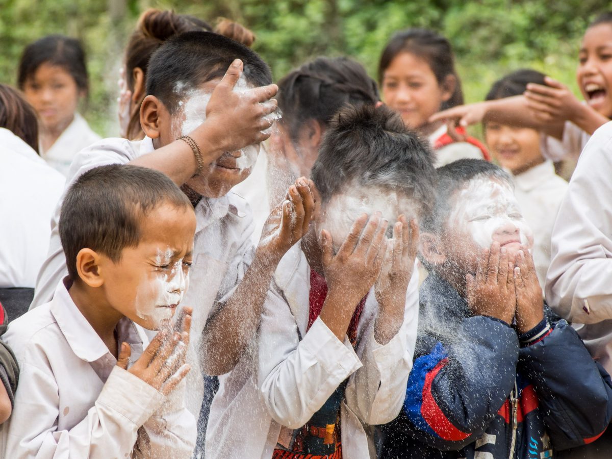 Children play game involving smearing their faces with flour