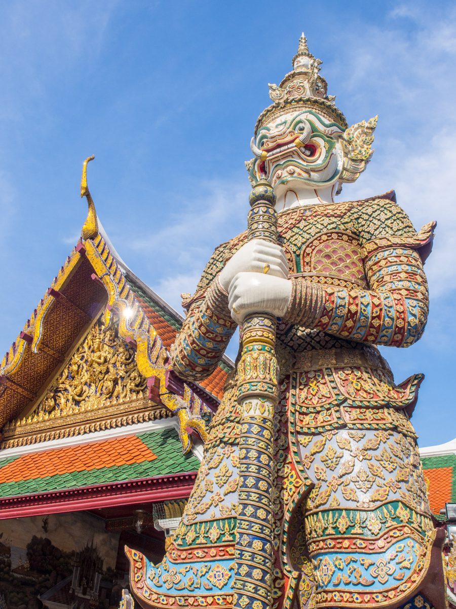 Huge gold and multi-colored statue of snarling demon guardian at temple entrance