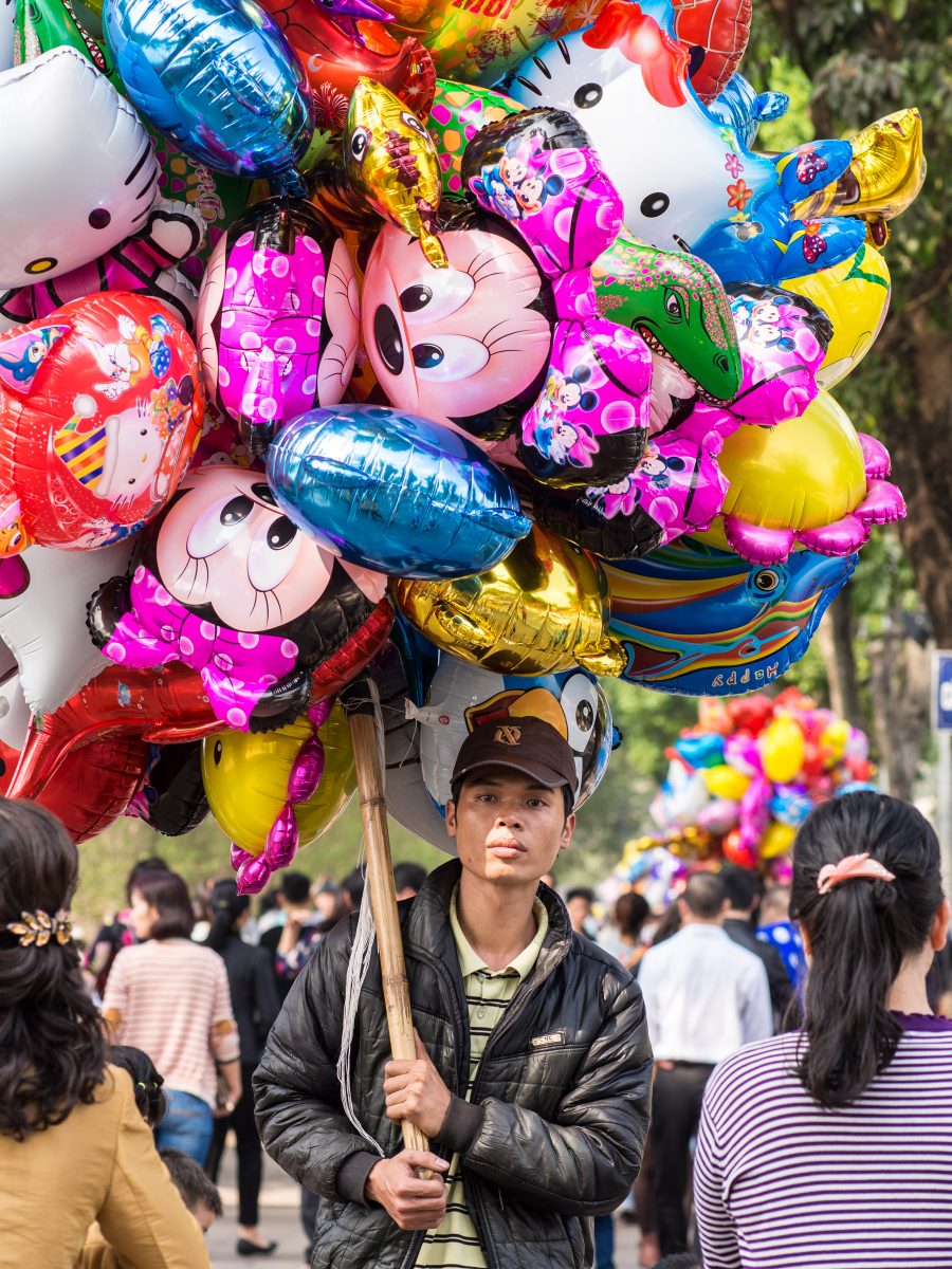 Man selling balloons on a long pole