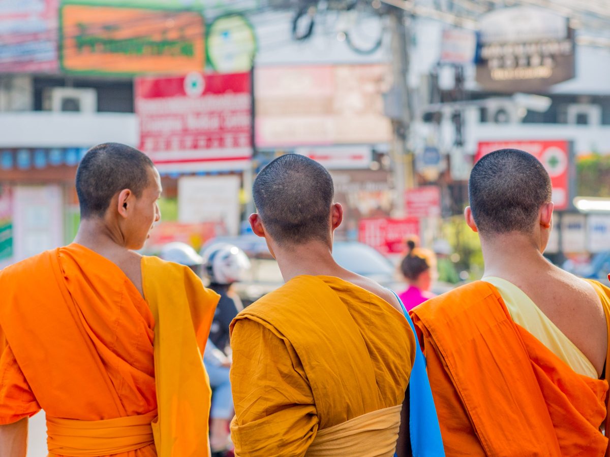 Three monks in orange robes from behind