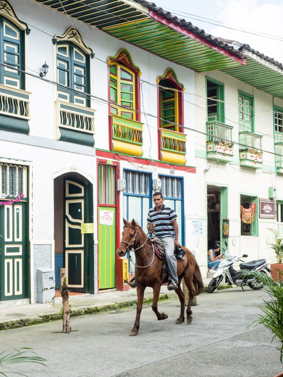 Man riding house down street with colorful doors