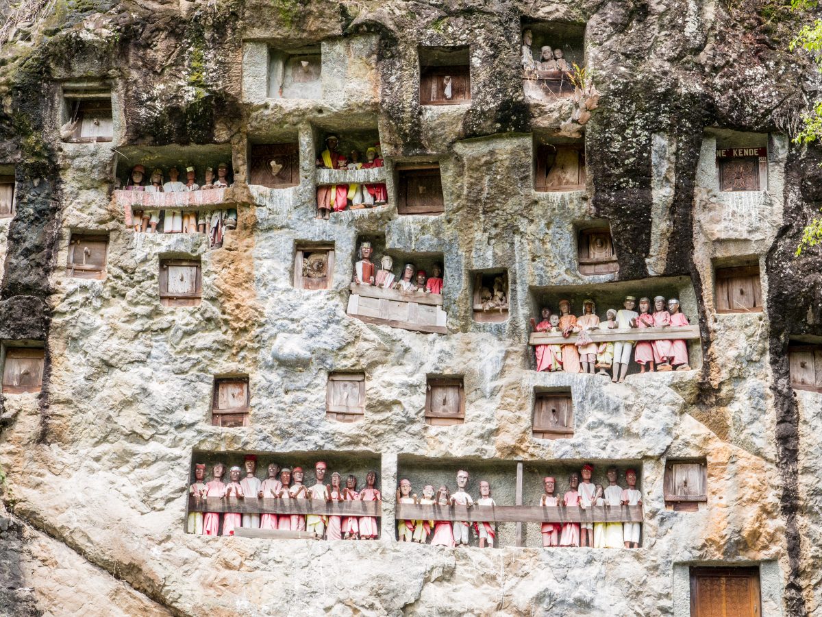 Rock face with small carved figures and tombs