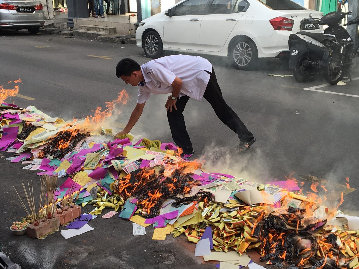 Man lighting paper money on fire in street