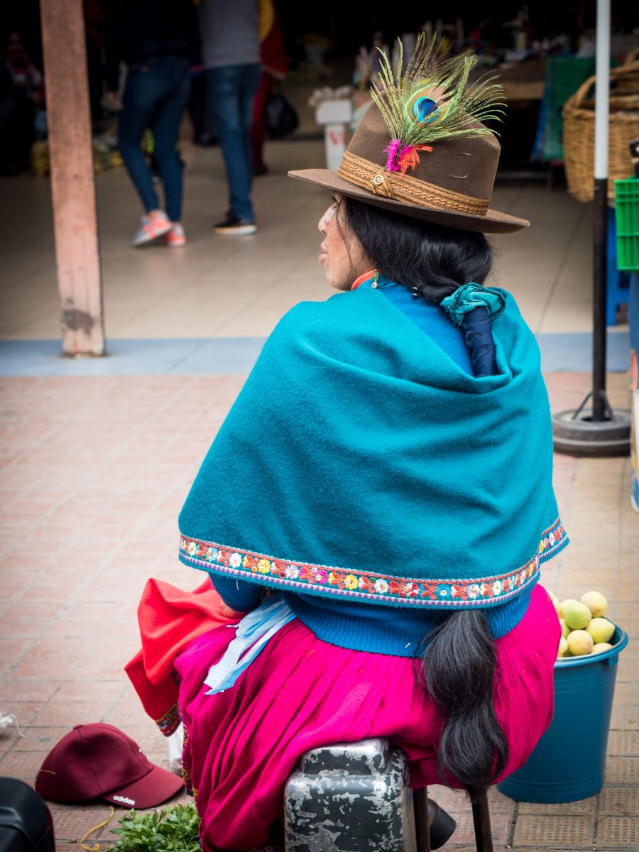 Indigenous woman in colorful clothes with peacock feather in hat