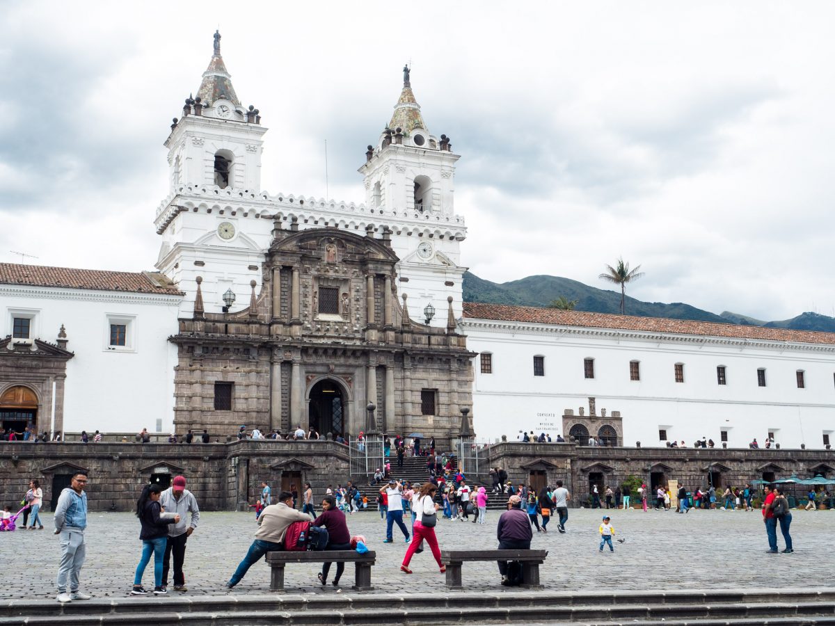 Plaza with people and white church in Quito, Ecuador